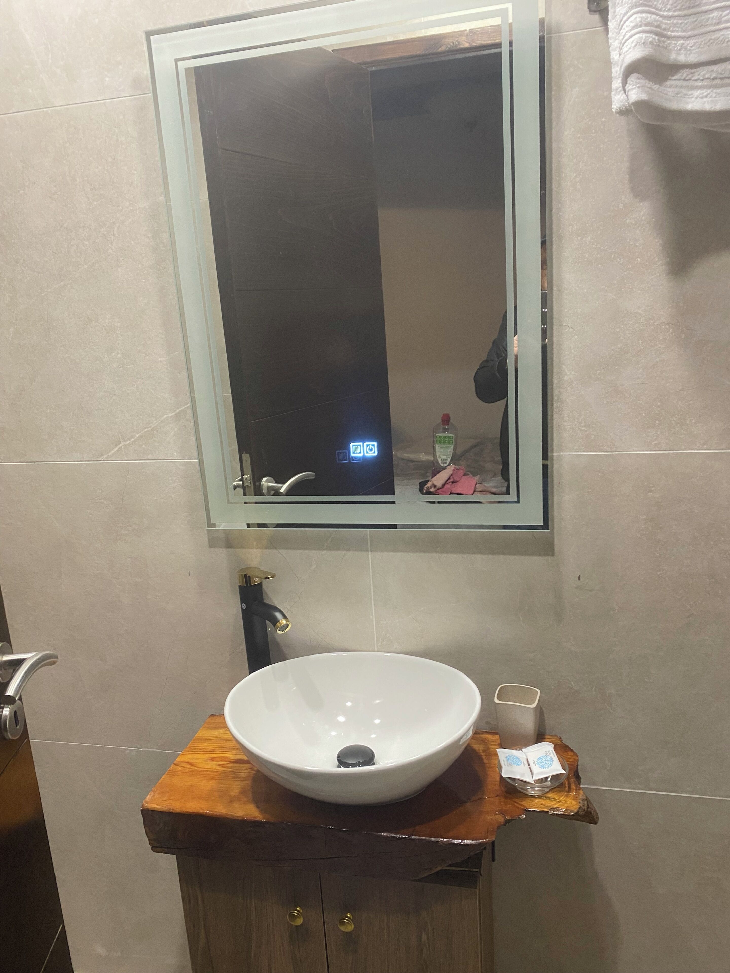 Une salle de bain avec un lavabo blanc, un miroir et un meuble-lavabo en bois.
