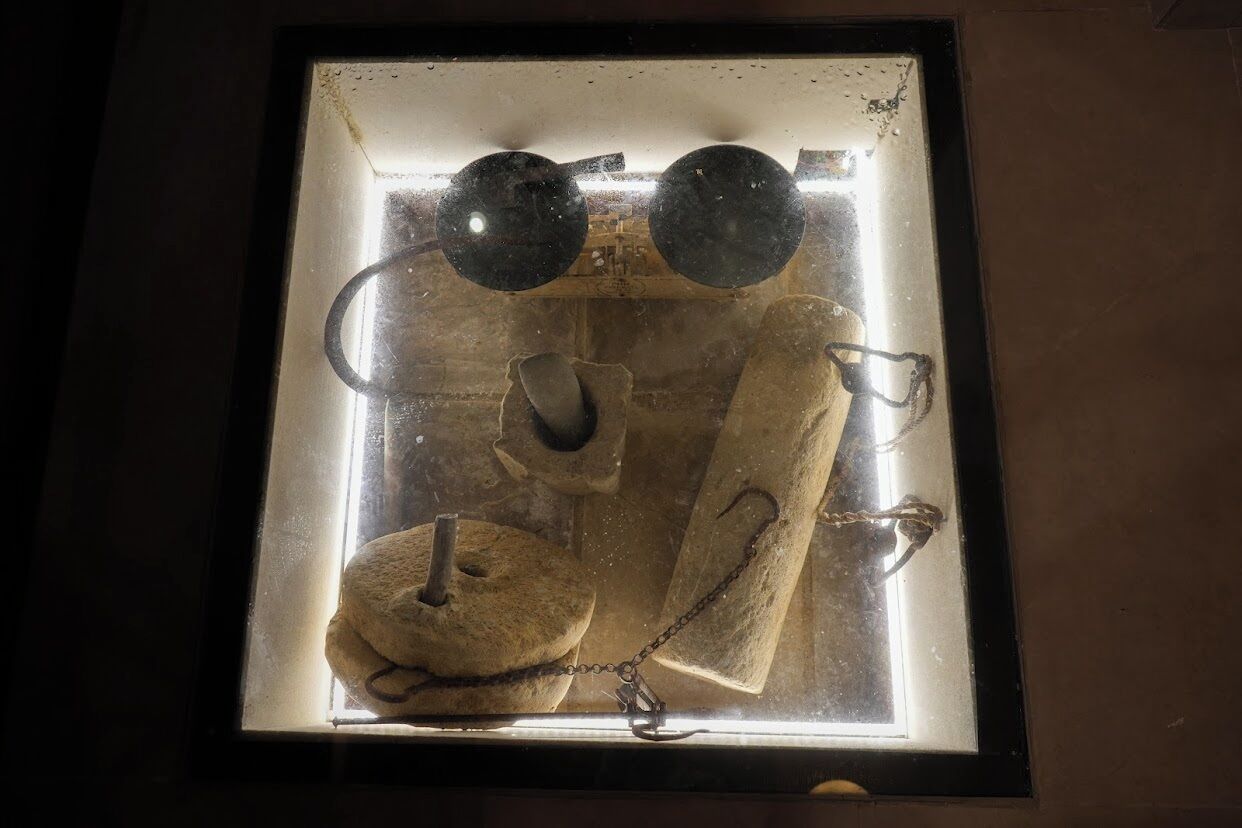 A framed picture of a vintage object with a chain and a hook, possibly a piece of jewelry or a decorative item.