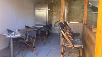 Una cucina rustica con travi in legno, un frigorifero e un'area pranzo con sedie in vimini e un tavolo in vetro.