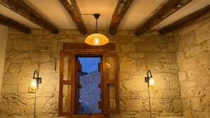 A stone-walled bathroom with a wooden-framed window, two wall-mounted lights, and a ceiling light fixture. - Vouni Calais  (Vouni)
