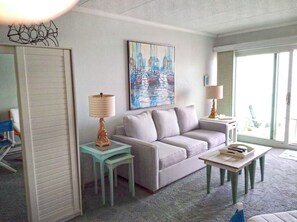 Ein Wohnzimmer mit einer Couch, zwei Lampen, einem kleinen Tisch und einem Bild an der Wand.