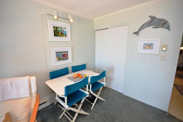 En matplats med ett vitt bord och blå stolar, inramade tavlor på väggen och en delfindekoration.