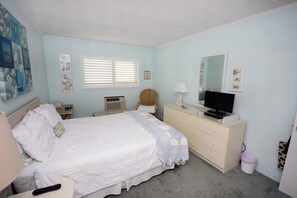 Ein Schlafzimmer mit Bett, Kommode, Fernseher und Bildern an den Wänden.