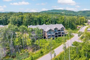 A multi-story building with a large driveway and surrounded by dense forest. - Tremblant Prestige - Verbier 10-203 (Mont-Tremblant)