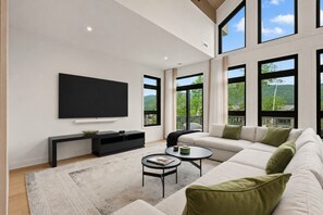 A modern living room with a large TV, a sofa, a coffee table, and a console table. - Tremblant Prestige - Verbier 10-203 (Mont-Tremblant)