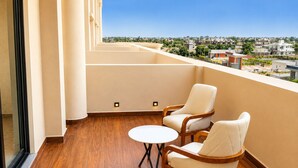 A balcony with two chairs and a small table, wooden flooring, and a view of a cityscape. - LUXURIA INN BY CHANDAN (Vanthli)