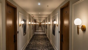 A hotel hallway with doors numbered 421, a marble floor, and wall-mounted lights. - LUXURIA INN BY CHANDAN (Vanthli)