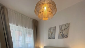 Ein Hotelzimmer mit einem großen Bett, zwei Nachttischen, einer Hängelampe und einem Bild an der Wand.