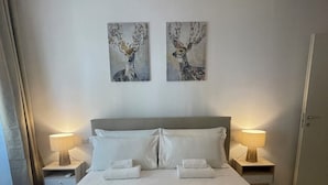 Ein Hotelzimmer mit einem großen Bett, zwei an der Wand befestigten Bildern, Nachttischlampen und einer Tür.