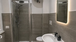 Ein modernes Badezimmer mit einer gläsernen Duschkabine, einem Standwaschbecken und einem wandmontierten WC.