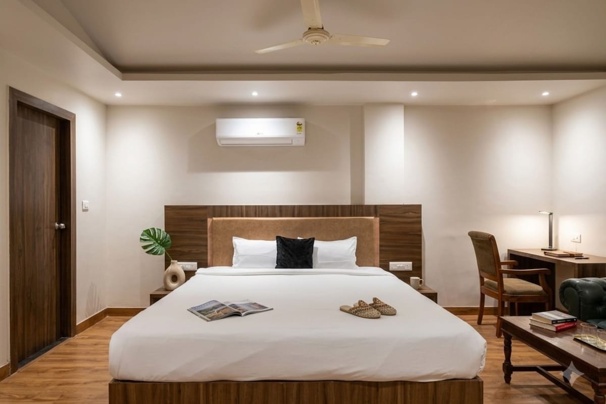 Habitación de hotel con una cama grande, un escritorio, una silla y un ventilador de techo.