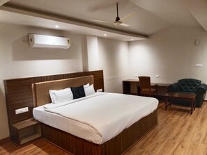 Habitación de hotel con una cama grande, un escritorio, una silla y un ventilador de techo.