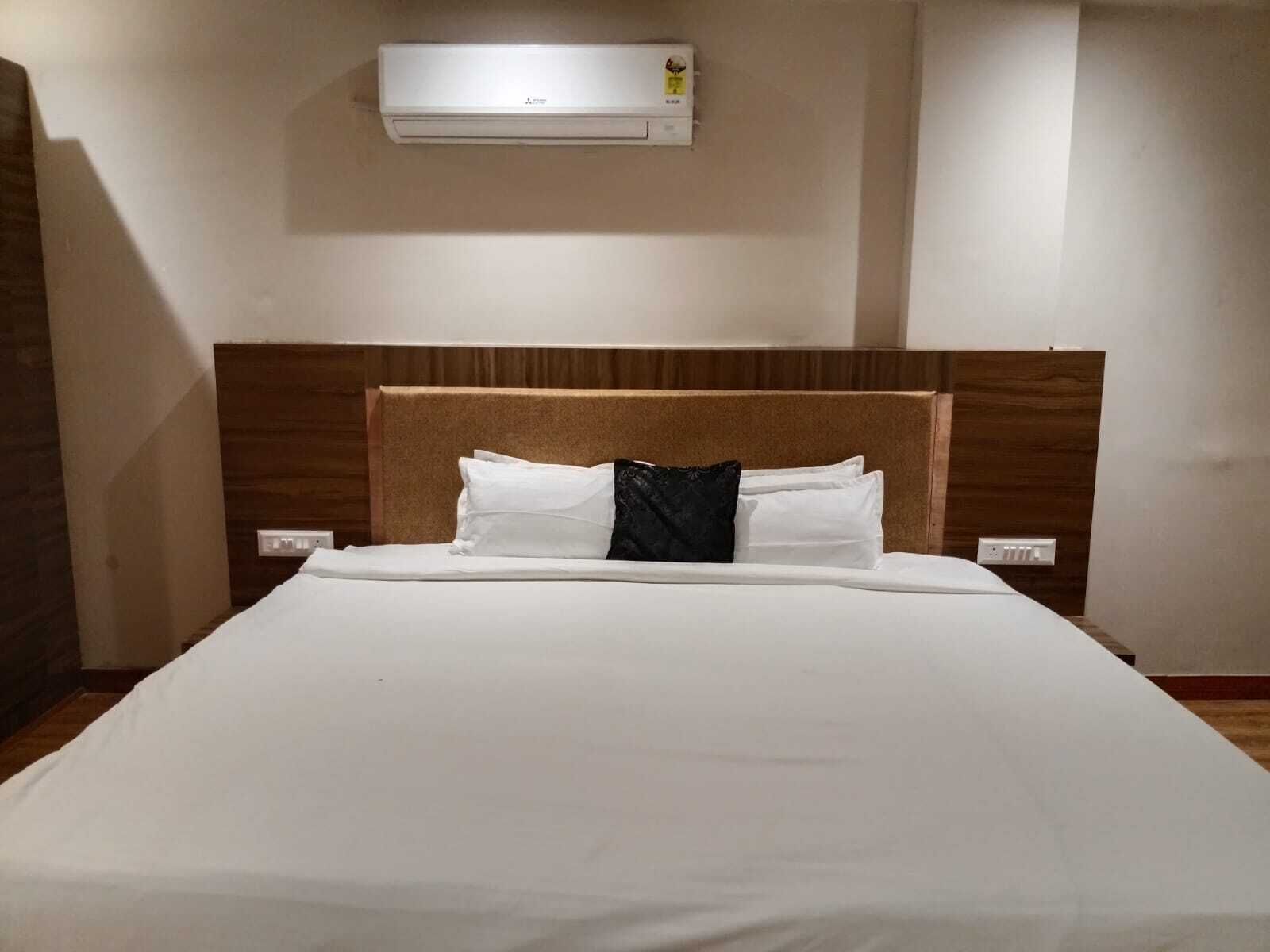 Ett hotellrum med en säng, en sänggavel och en luftkonditioneringsanläggning som är monterad på väggen.