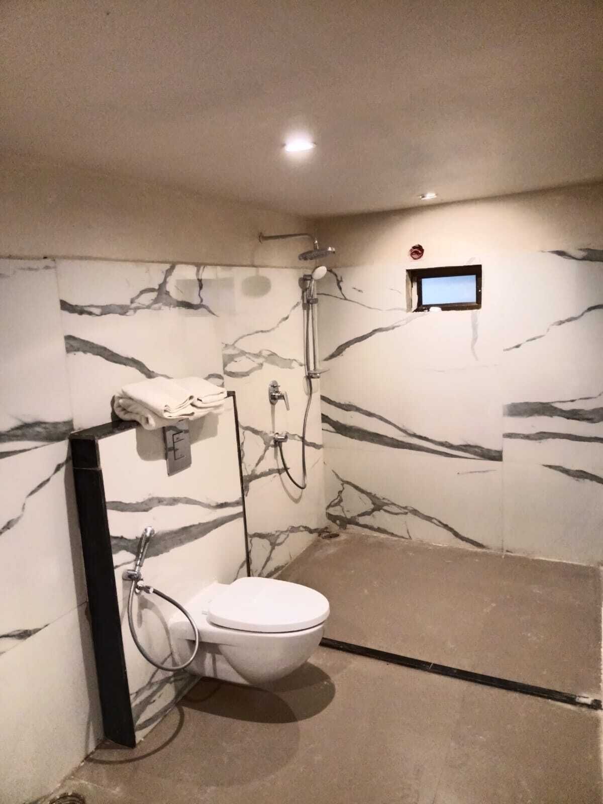 A bathroom with a toilet, shower, and a small window.