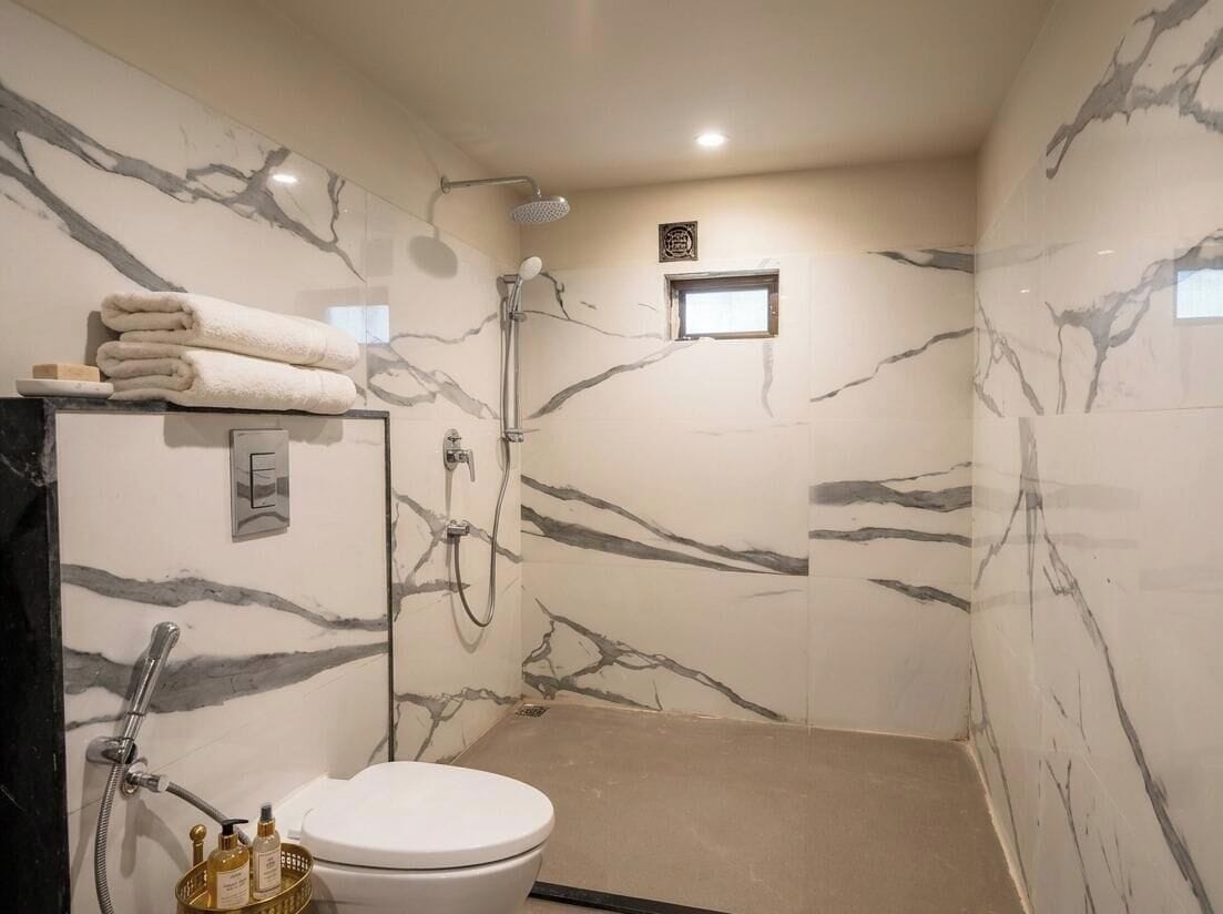 Un baño con inodoro, ducha y paredes de mármol.