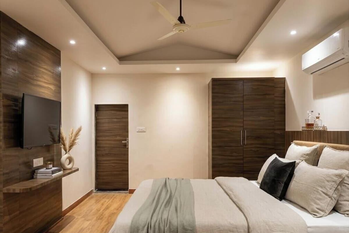 Un dormitorio moderno con cama, armario, televisión y ventilador de techo.