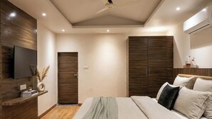 Un dormitorio moderno con cama, armario, televisión y ventilador de techo.