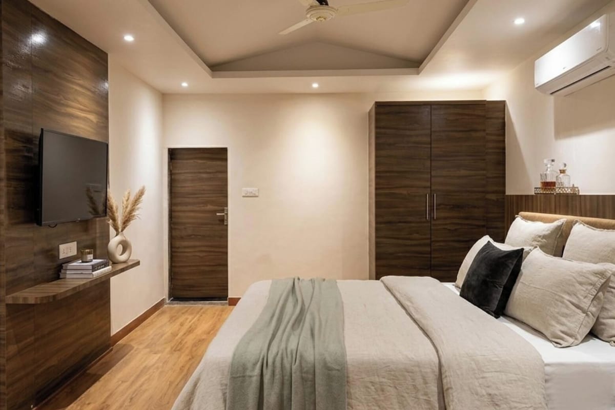 Un dormitorio moderno con cama, armario y televisor montado.