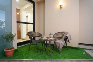 Un pequeño espacio al aire libre con dos sillas, una mesa y una planta en maceta.
