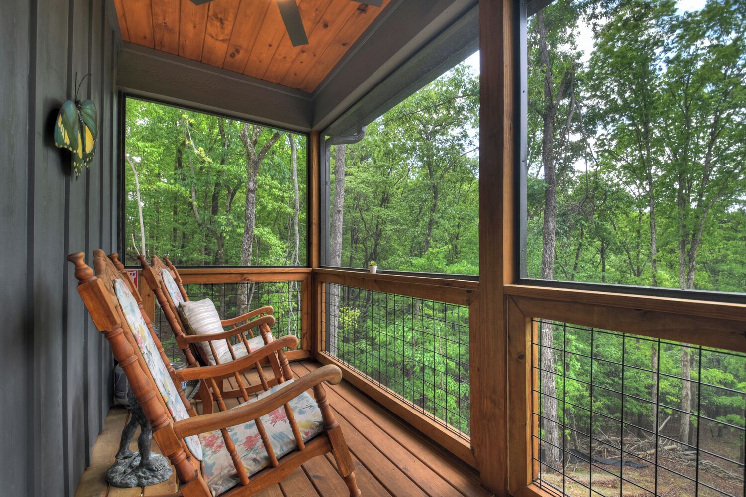 A wooden porch with two rocking chairs and a view of a forest.