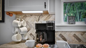 Eine Küche mit Kaffeemaschine, Tassenhalter und einem Schild über Kaffee.