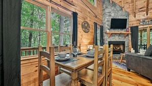 Ein Holzblockbau-Innenraum mit Esstisch, Stühlen, Kamin und einer Couch.