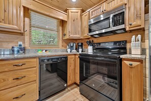 A kitchen with wooden cabinets, a microwave, a dishwasher, and an oven. - Private, dog-friendly cabin rental, tons of deck space, outdoor fireplace, hot tub (Morganton)