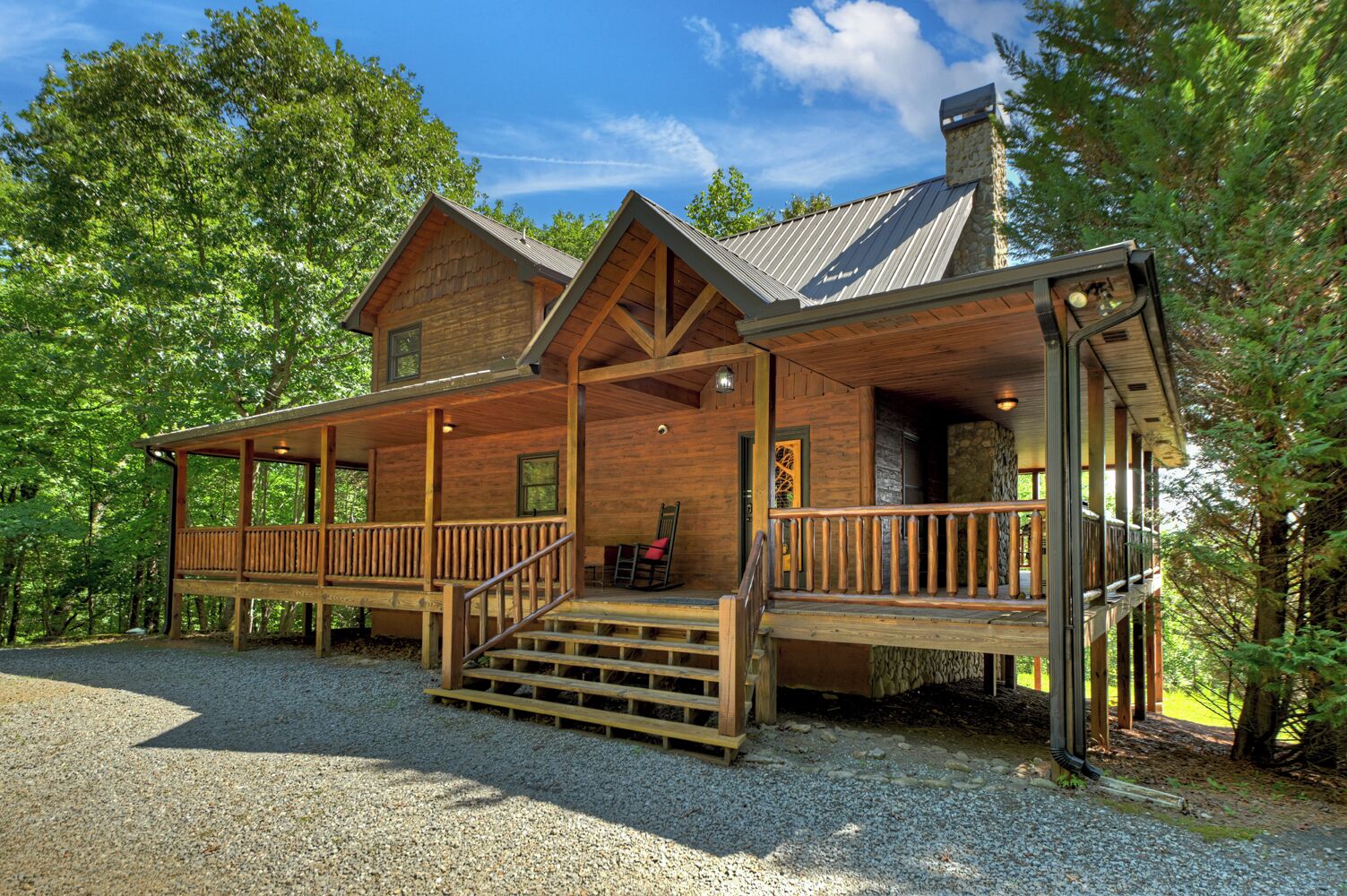 Eine Holzhütte mit Veranda, Schornstein und einem Schotterweg.
