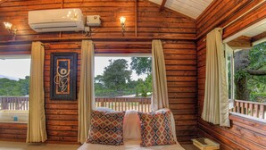 Uma cabana de madeira com cama, cortinas, um quadro e um aparelho de ar condicionado.