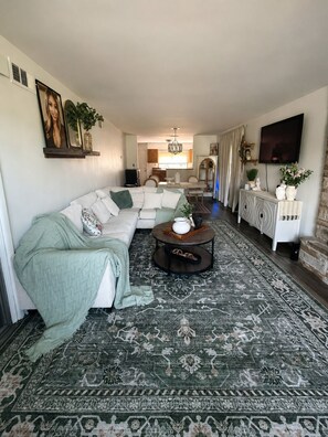 A living room with a sectional sofa, a coffee table, a patterned rug, a TV, and a fireplace. - Private & Peaceful Farmhouse 0.6 Miles from University of Chicago Hospital (Harvey)