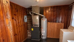 Uma lavanderia equipada com máquina de lavar, secadora, aquecedor de água e sistema de ventilação.