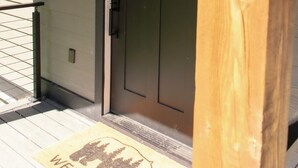 Una porta in legno con una targa con il numero '4', un tappetino d'ingresso e una ringhiera metallica su un portico.