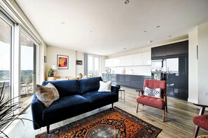 Un saló modern amb un sofà blau fosc, un armari vermell i una catifes amb disseny.