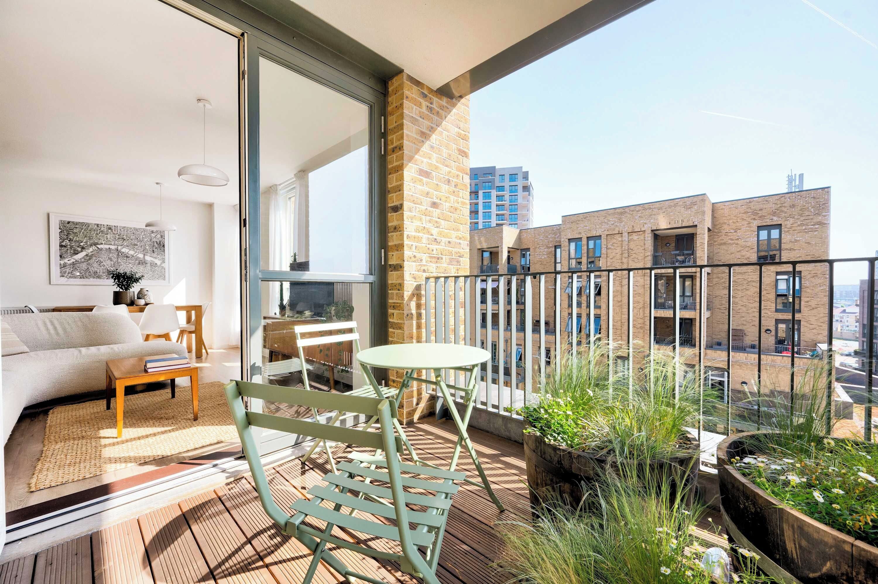 Een balkon met een bank, tafel, stoelen en potplanten.