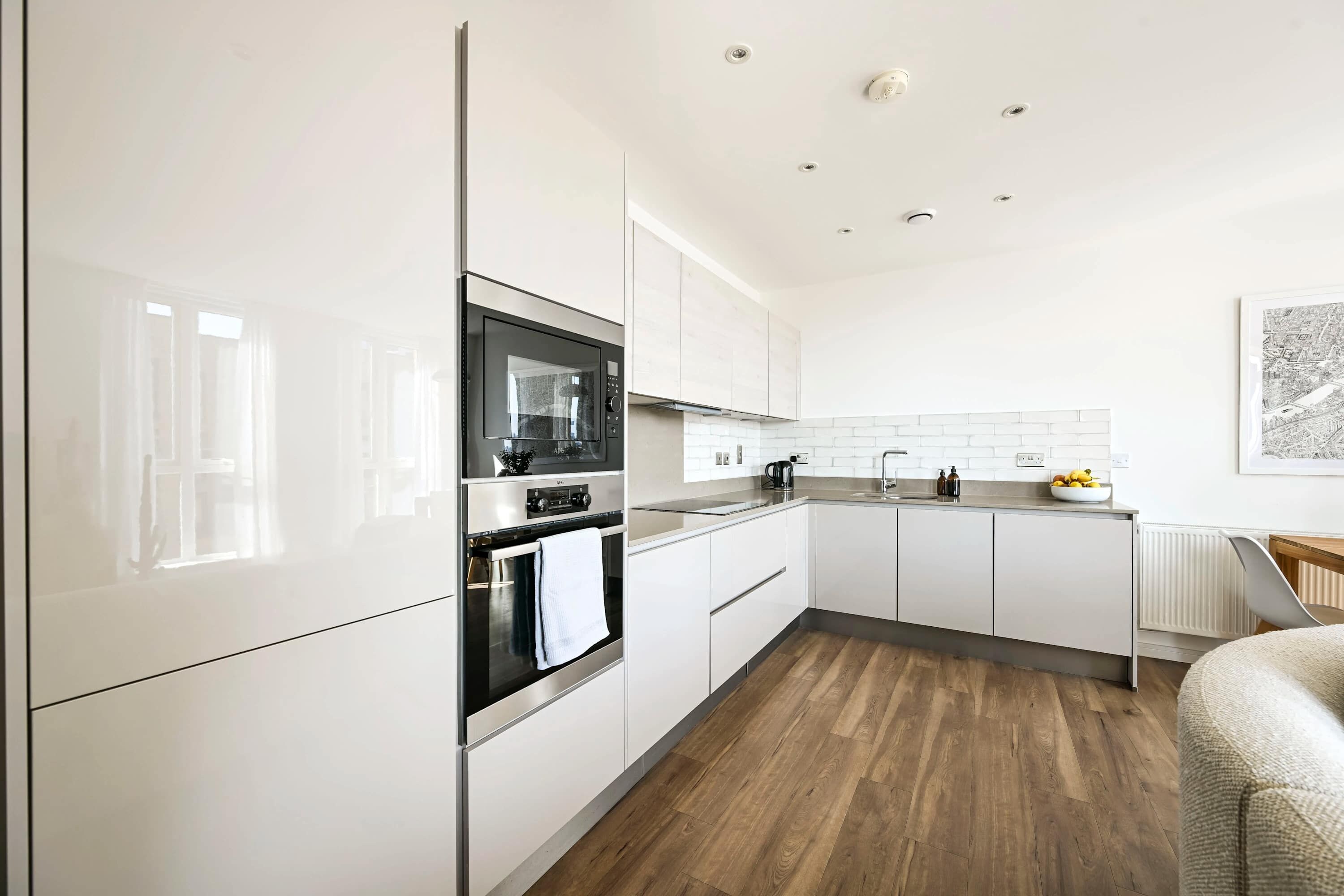 A modern kitchen with white cabinetry, a built-in oven, and a microwave.