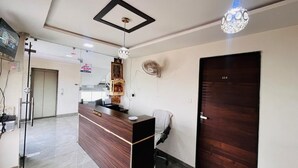 Un área de recepción con un escritorio de madera, un ventilador en la pared, una puerta con el número 314 y un aplique en el techo.
