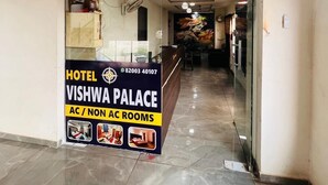 Un pasillo de hotel con una recepción, un cartel que indica habitaciones con aire acondicionado y sin aire acondicionado, y un mural en la pared.