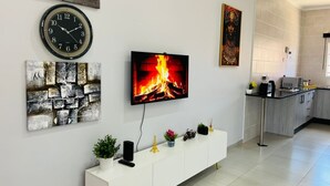 Un soggiorno moderno con una TV a schermo piatto, una sveglia e arte astratta alle pareti.