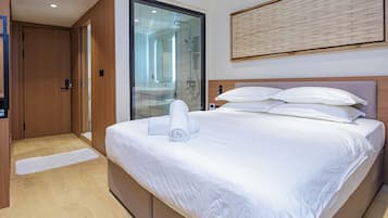 A hotel room with a large bed, a shower, and a view through a glass door.