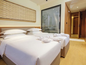 Una habitación de hotel con dos camas, un ventanal grande y una puerta de madera.