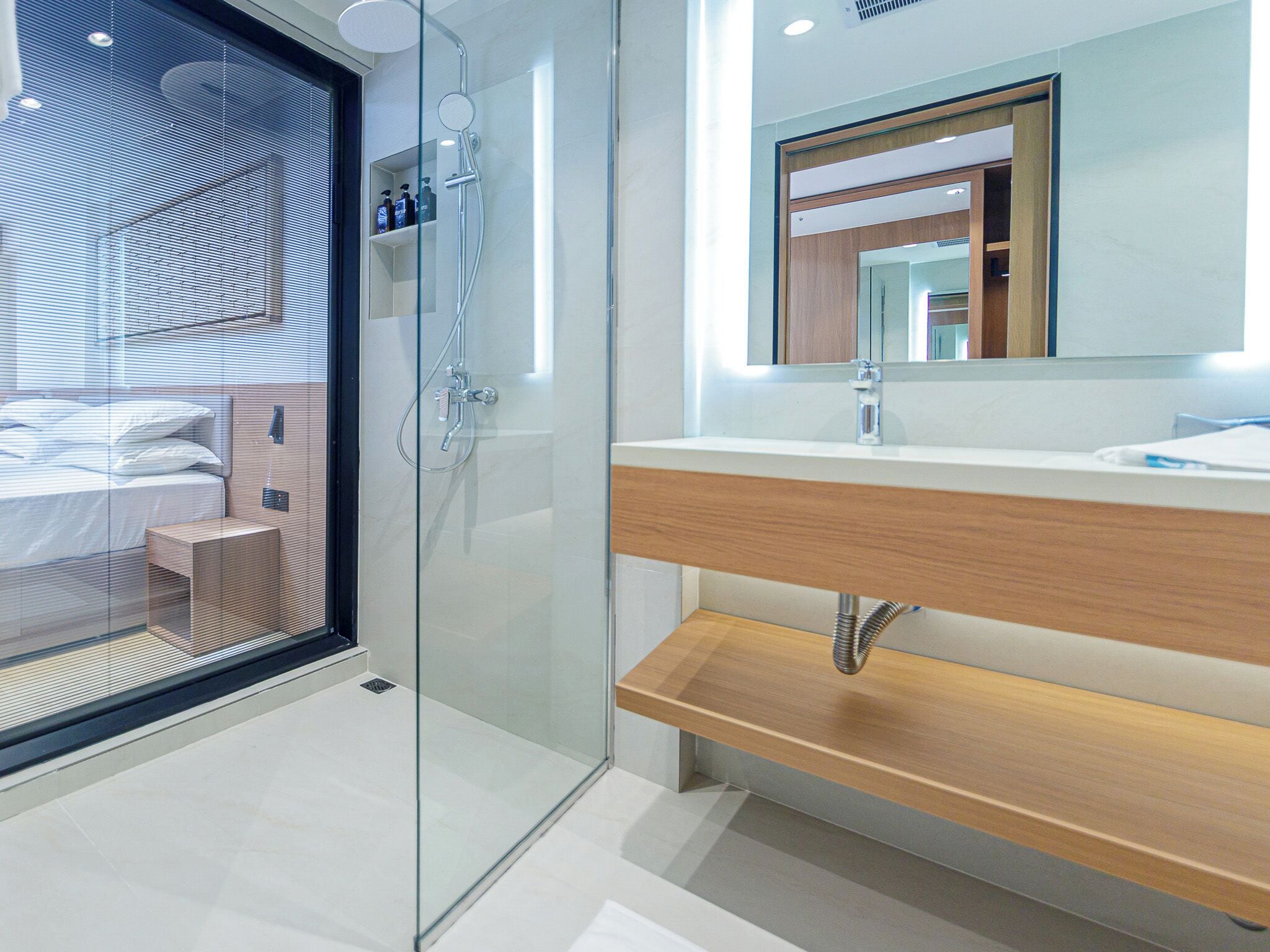 A modern bathroom with a glass shower enclosure, a wooden vanity, and a large mirror.