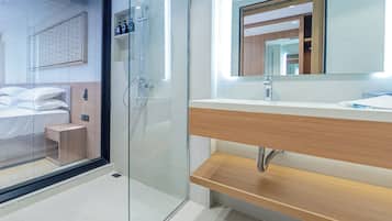 A modern bathroom with a glass shower enclosure, a wooden vanity, and a large mirror.