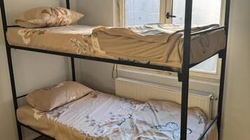 Ein Schlafraum mit Etagenbett, Fenster, Holzboden und Heizkörper.