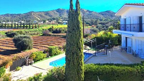 A residential property with a swimming pool, a balcony with outdoor furniture, and a view of a vineyard and hills. - Villa Koryfi - Argaka - 3 Bedroom villa minutes walk from the beach (6 guests) (Argaka)