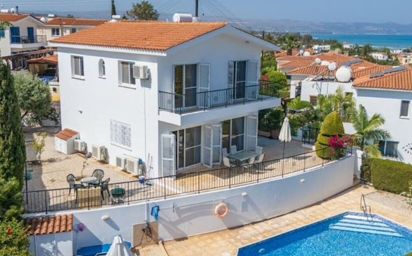 Un edificio a due piani con un balcone, una piscina e vista sul mare.