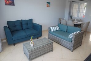 A living room with a blue sofa, a wicker sofa, and a coffee table with a vase. - No. 17 - The Grand Gaube Retreat – Pool, Turquoise Sea Just Steps Away (Grand Gaube)