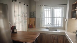 A kitchen with a wooden table, a coffee maker, and a window with a view. - No. 17 - The Grand Gaube Retreat – Pool, Turquoise Sea Just Steps Away (Grand Gaube)