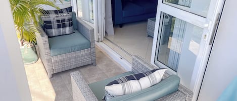 Un patio soleado con muebles de mimbre y una planta en maceta.