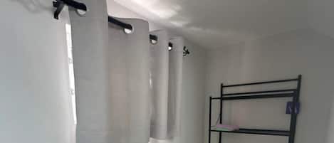 A small, clean bathroom with a toilet, a shelf with toiletries, and a shower curtain.