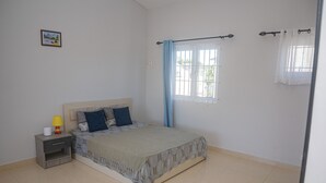 A bedroom with a bed, nightstand, lamp, window with curtains, and a wall-mounted picture. - No. 17 - The Grand Gaube Retreat – Pool, Turquoise Sea Just Steps Away (Grand Gaube)